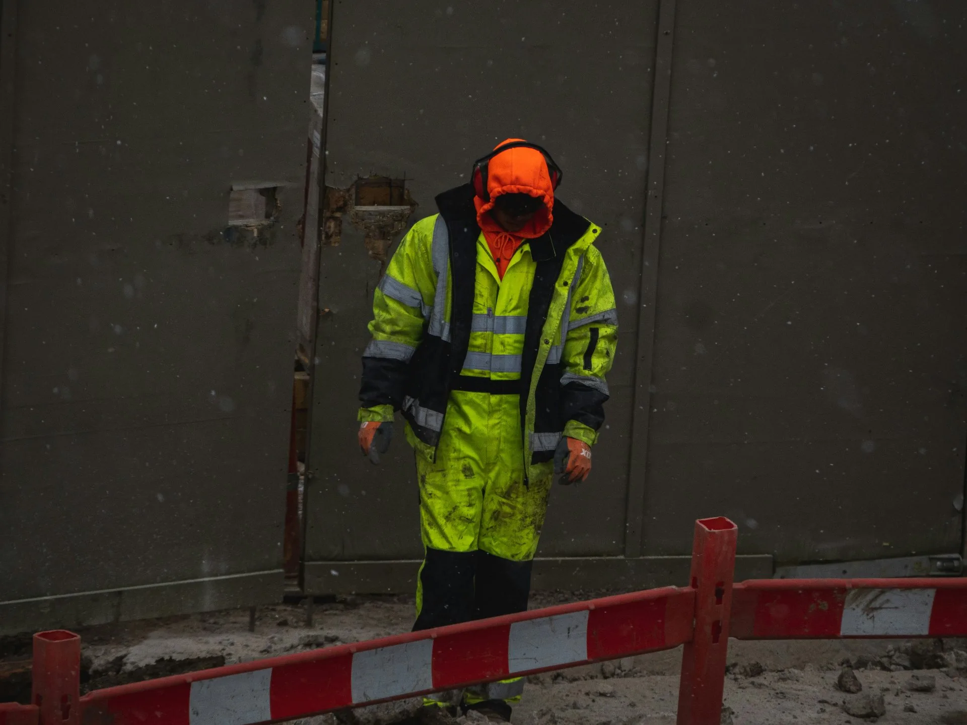 LYTH EN 20471 hi-vis workwear on a construction site in snow — fluorescent yellow / green jacket, bib overalls and orange hooded jacket
